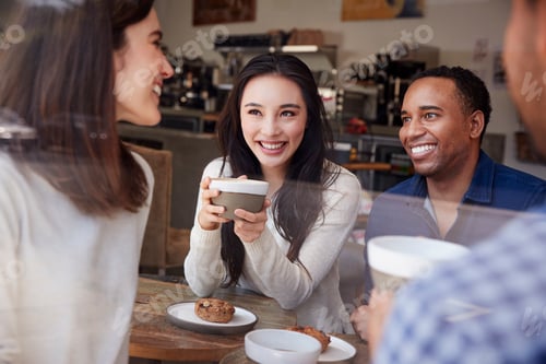 Preview: Four smiling friends having coffee at coffee shop, close up