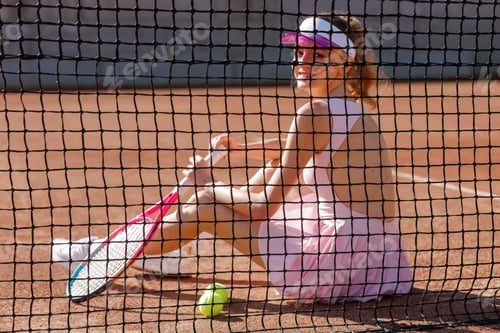 Preview: Female Tennis Player Sitting on Clay Court Behind Net Relaxing