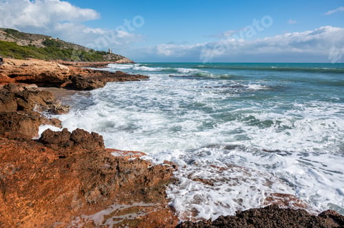 Preview: Closeup shot of huge, beautiful sea waves touching the rocky coast with a blue sky background