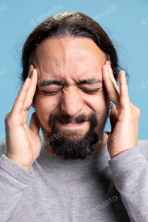 Preview: Stressed overwhelmed adult dealing with a headache against blue background