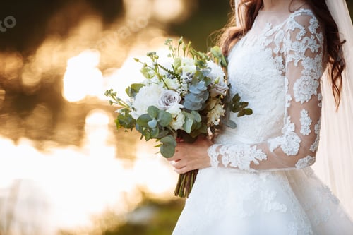 Preview: The bride in an elegant wedding dress holds a beautiful bouquet of different flowers green leaves