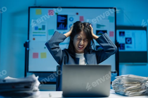 Preview: Tired businesswoman experiencing burnout in her office late at night. Overwhelmed by work pressure.