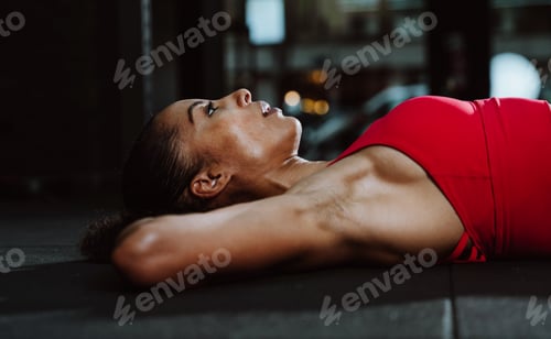 Preview: Fit young woman in red sport outfit making workout in the gym