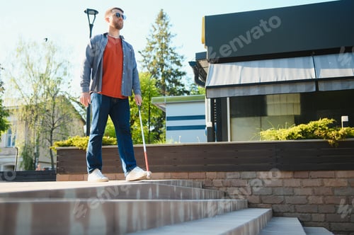 Preview: Young handsome blinded man walking with stick in town