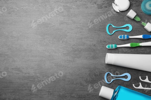 Preview: Flat lay composition with tongue cleaners and teeth care products on grey background. Space for text