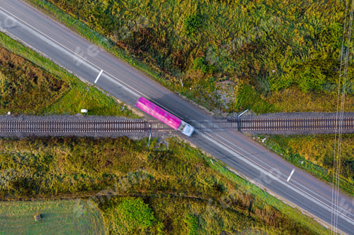 Preview: aerial view of railroad tracks crossing a asphalt road with cars in rural area