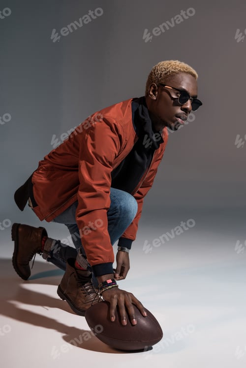 Preview: Stylish young african american man holding rugby ball on floor