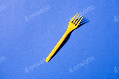 Preview: top view of yellow plastic fork isolated on violet