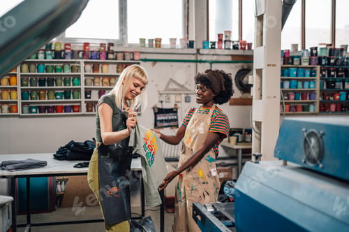 Preview: Interracial printing shop female workers doing quality control of product