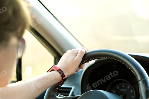 Preview: Close up view of woman holding steering wheel driving a car on city street on sunny day