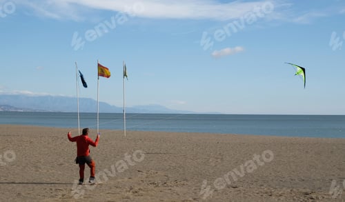 Preview: Man flying a kite at sunny day on the sandy beach of the Mediterranean Sea in Spain.