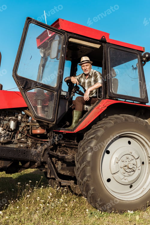 Preview: senior self-employed farmer in straw hat driving tractor