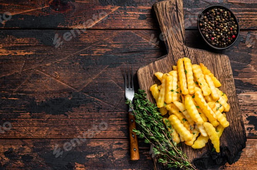 Preview: Baked Crinkle French fries potatoes sticks or chips on a wooden board.