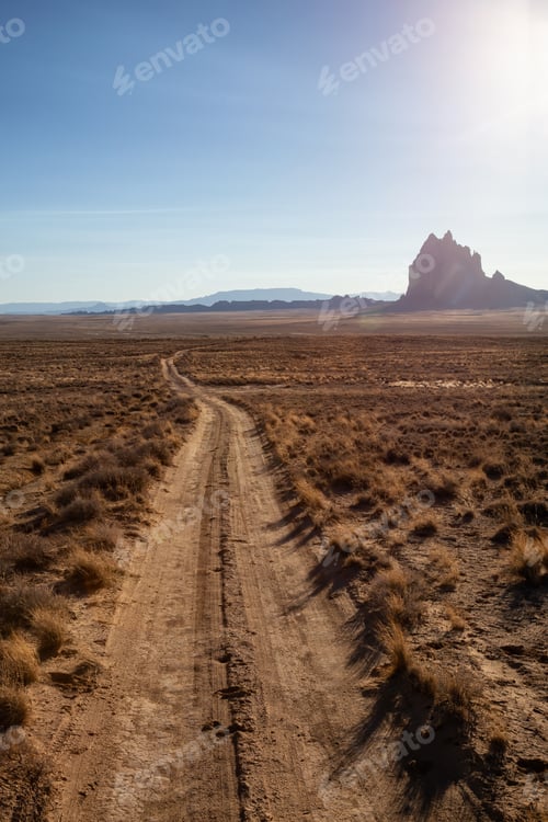 Preview: Dirt road in the dry desert with a mountain peak in the background
