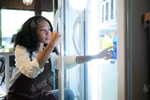 Preview: The owner of a coffee shop looks inside the refrigerator to retrieve chilled food