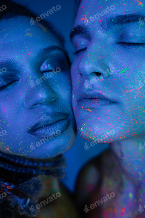 Preview: closed up portrait of charismatic man and appealing african american woman in colorful body paint