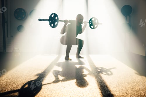 Preview: Strong man lifting barbell in gym in sunlight
