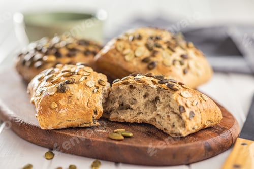 Preview: Whole grain bun with pumpkin seeds on cutting board.