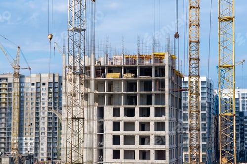 Preview: crane and a building under construction against a blue sky background