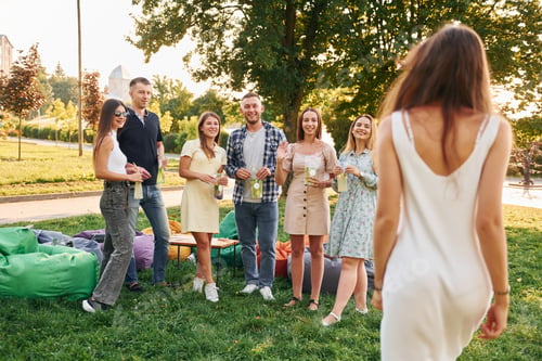 Preview: Standing with cocktails. Group of young people have a party in the park at summer daytime