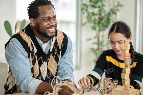 Preview: Smiling African American teacher watching student arranging wood toy in the classroom