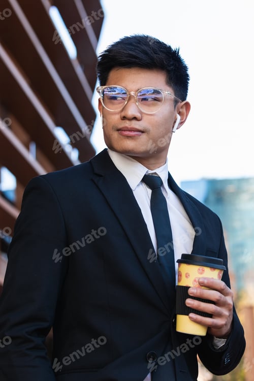 Preview: Handsome ethnic businessman with takeaway coffee in city