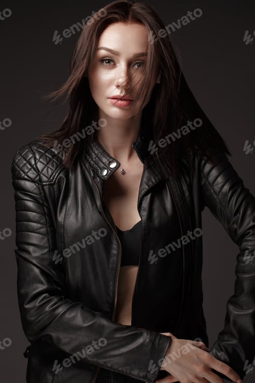 Preview: Daring girl model in black leather dress, style of rock, dark make up and beauty hair.