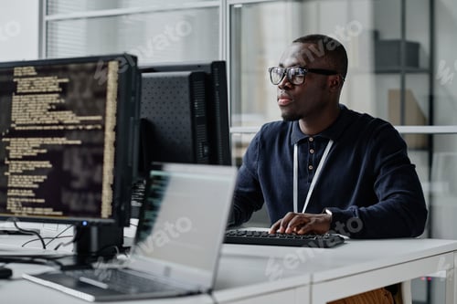 Preview: African American young developer in eyeglasses concentrating on his online work on computer sitting