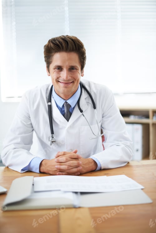 Preview: Portrait of a positive-looking young doctor sitting at his desk