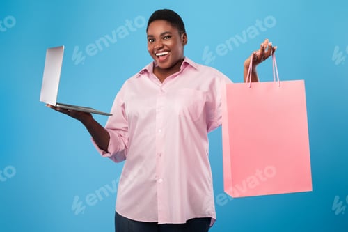 Preview: African american woman holding laptop and shopping bag, blue background