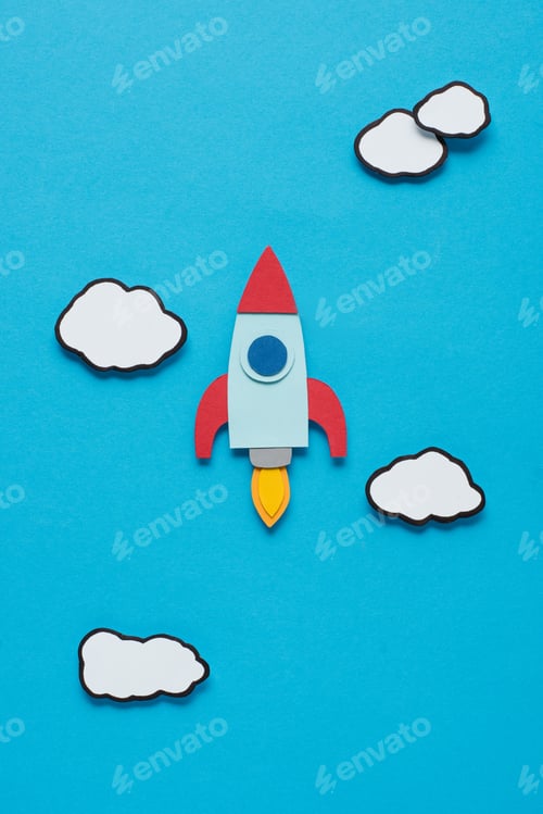 Preview: top view of paper rocket with clouds on blue background, setting goals concept
