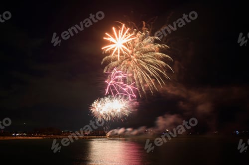 Preview: Aerial view of bright fireworks exploding with colorful lights over sea shore