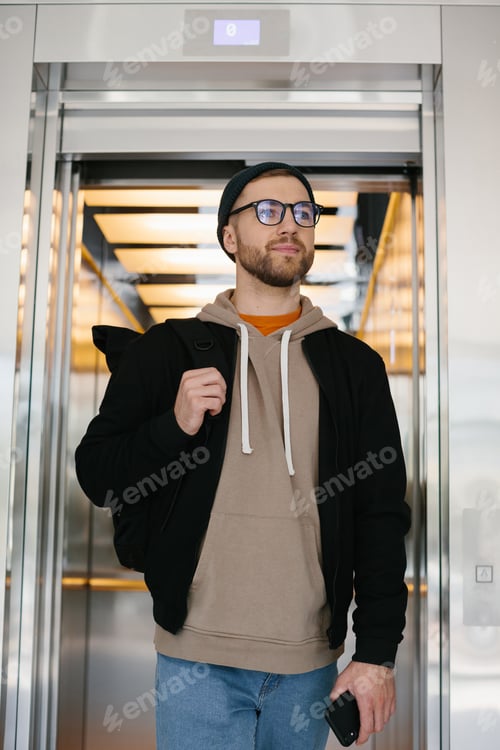 Preview: A young man uses an elevator. IT specialist on the background of an elevator in an office building.