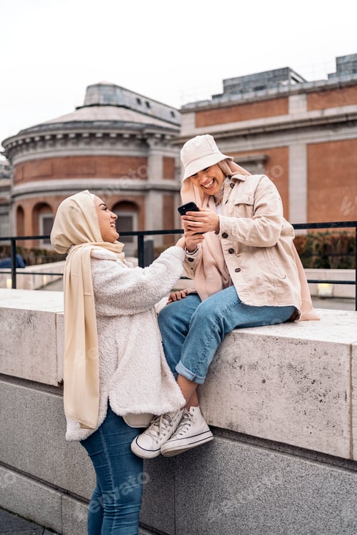 Preview: Two Young Women Laughing While Looking at Phone
