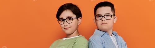 Preview: Two Boys Wearing Glasses Smile Against Orange Background