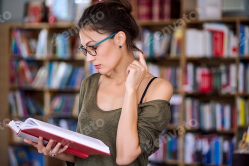 Preview: Young simpatic woman reading a book plaing with hair