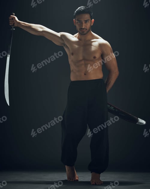 Preview: Full length shot of a handsome young man standing alone in the studio and posing with a broadsword