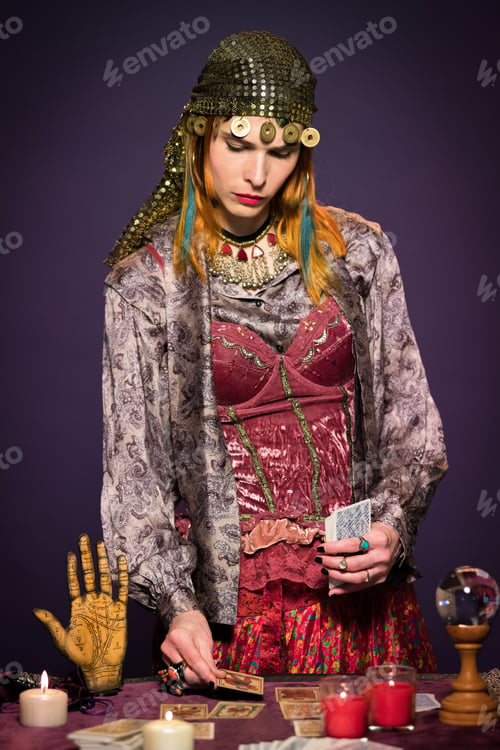 Preview: Concentrated female fortune teller laying out cards on table during divination
