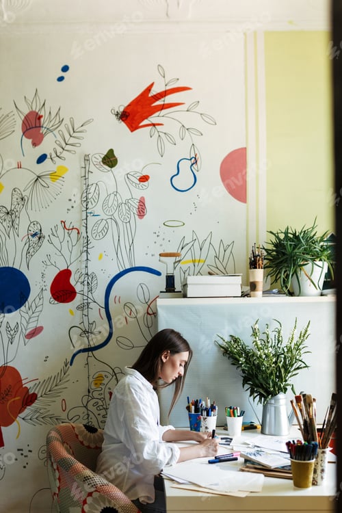 Preview: Young painter in shirt at the desk thoughtfully drawing with big