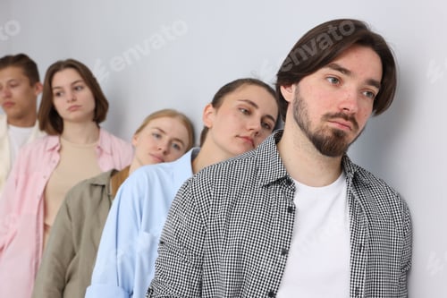 Preview: Group of people waiting in queue near light grey wall indoors