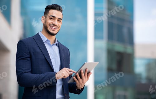 Preview: Good-looking arab guy in formal wear using digital tablet