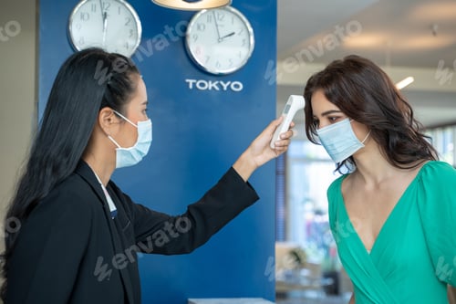 Preview: Check-in at the hotel.Reception wear protective face mask use infrared thermometer checker.