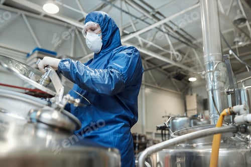 Preview: Man wearing protective gear opening tank at chemical plant or factory