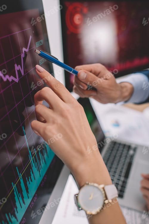 Preview: Cropped view of data analysts pointing on charts on computer monitors