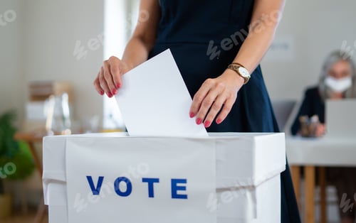 Preview: Unrecognizable woman putting her vote in the ballot box, usa and coronavirus elections