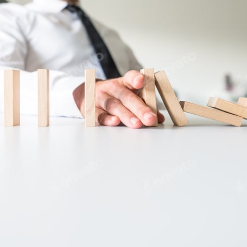 Preview: Businessman placing his hand to stop falling dominos