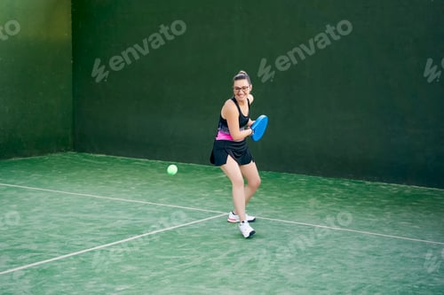 Preview: Sportswoman hitting padel ball with racket