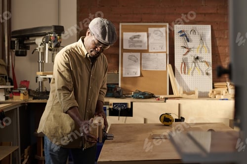 Preview: Black Senior Man as Carpenter Using Equipment in Woodworking Shop