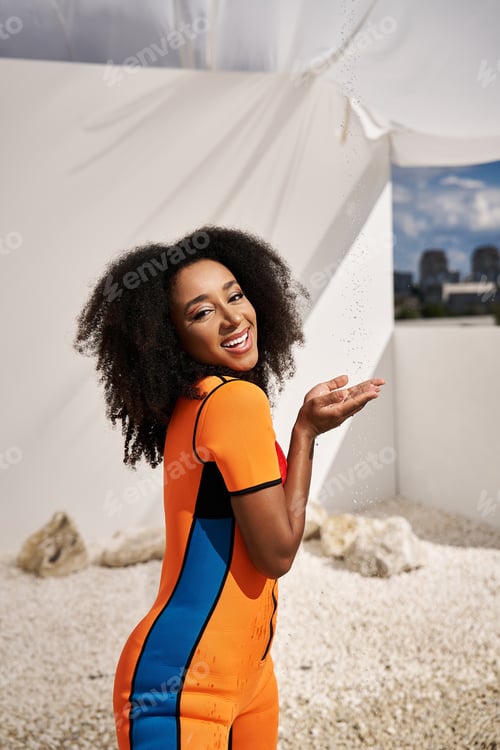 Preview: Stunning young African American woman in vibrant attire enjoying a sunny day outdoors
