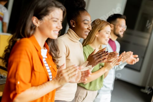 Preview: Young multiethnic startup team standing and applauding in the modern office